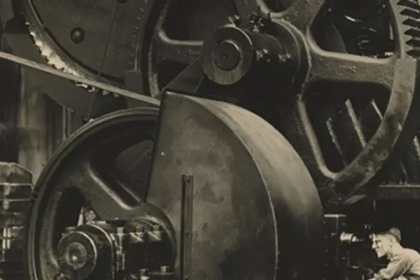 A person works below a massive set of gears multiple times larger than them.