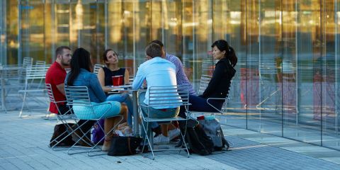 Executives sit at a table and talk outside on the HBS campus.