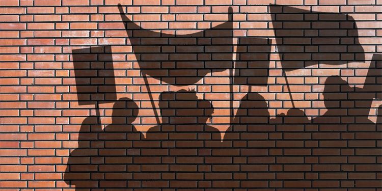 Shadow of protesters on a brick wall