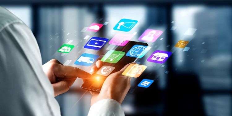 Business professional holding a mobile device with icons floating above it, including a shopping cart, megaphone, and house