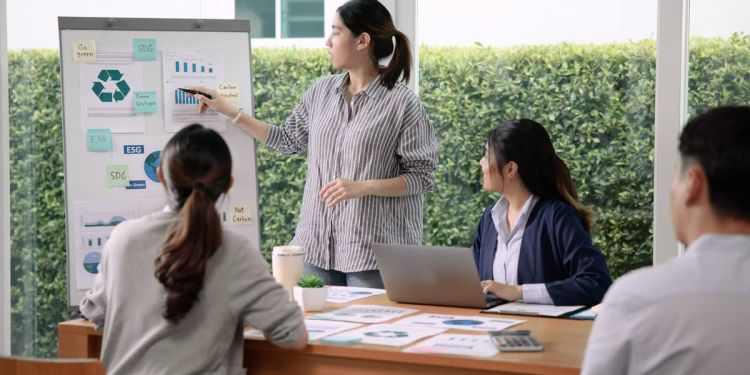 Team of four business professionals reviewing climate change strategies on an easel