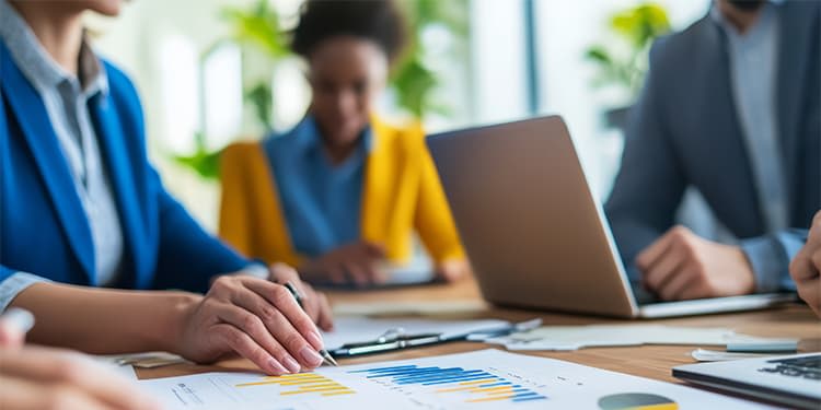 Business professionals sitting around a table analyzing performance gaps on paper graphs