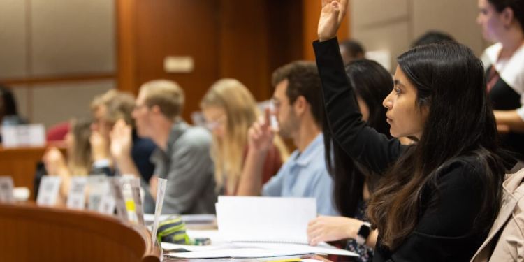 MBA student raising hand in Harvard Business School classroom