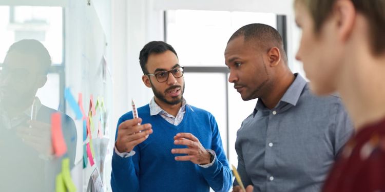 Business man leading team in problem-solving exercise with white board