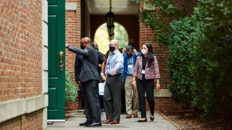 A diverse group of executives wearing masks enter a building on the HBS campus 