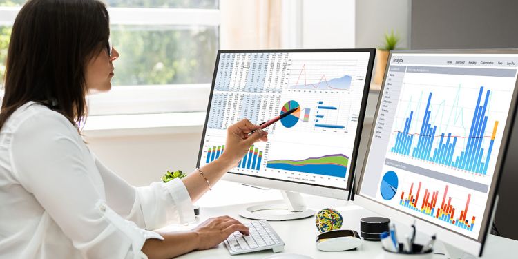 Business professional examining data analytics on computer screens