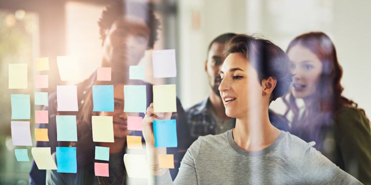 colleagues developing a business strategy using sticky notes on glass window