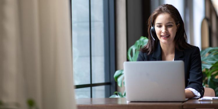 A customer service representitive at her laptop with a headset on speaking to a customer.