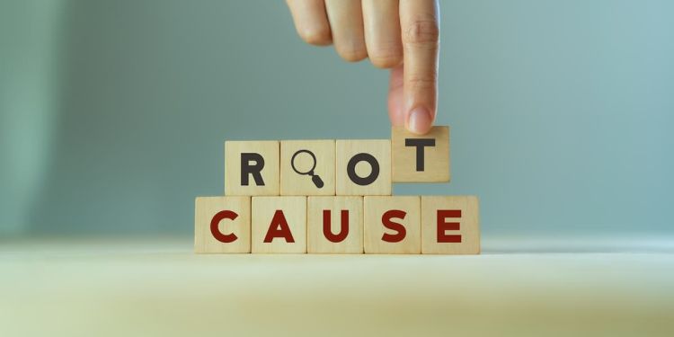 A hand stacking building blocks that read "root cause"
