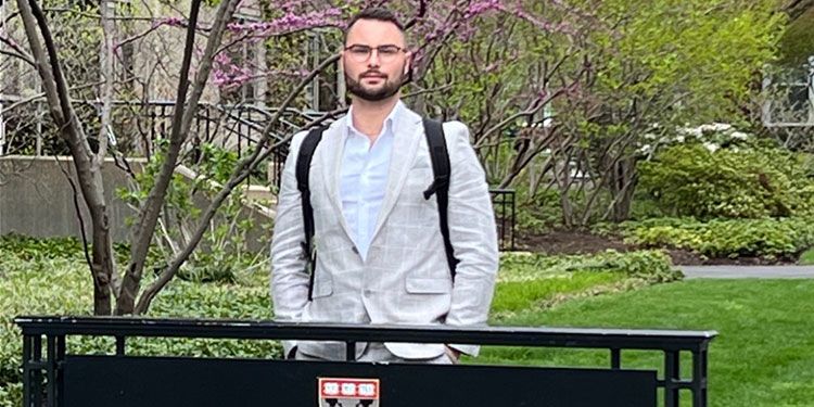 Chase Thomas standing behind the Harvard Business School sign