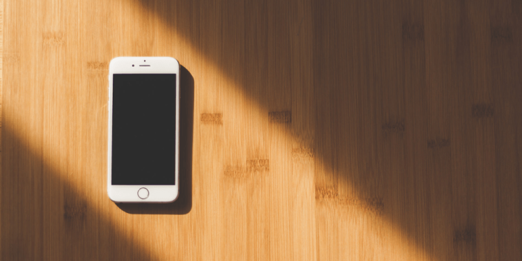 artful picture of an iPhone on a wooden surface with a light shining on it