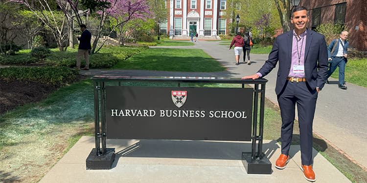 John Flores standing near the Harvard Business School sign on campus.