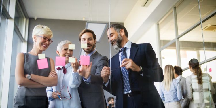 Colleagues strategizing with sticky notes through glass window