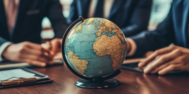 A globe on a wooden desk with two business professionals seated behind it