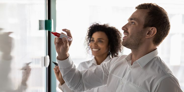 Employees creating a perceptual map on a whiteboard.
