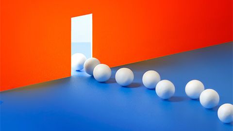 ping pong balls streaming across a blue floor and through a door in an orange wall