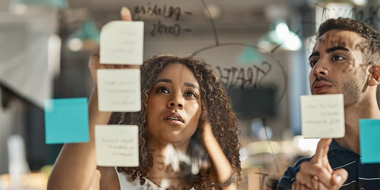 Two branding professionals working at a whiteboard with sticky notes